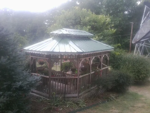 Green metal roof on a backyard gazebo surrounded by garden beds in Abilene
