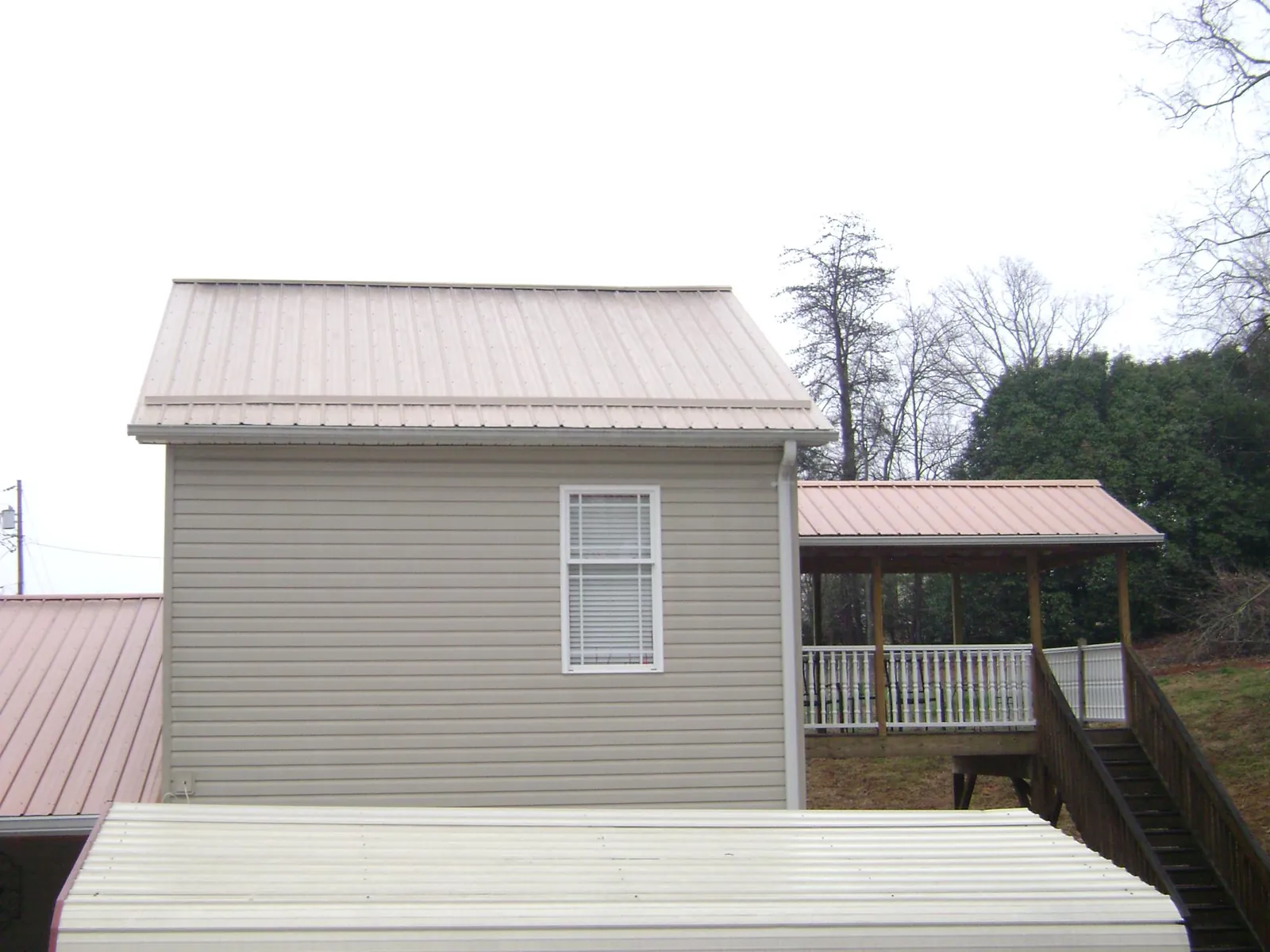 Tan metal roofs on a two story addition and attached porch, from a Roof Replacement job in Abilene